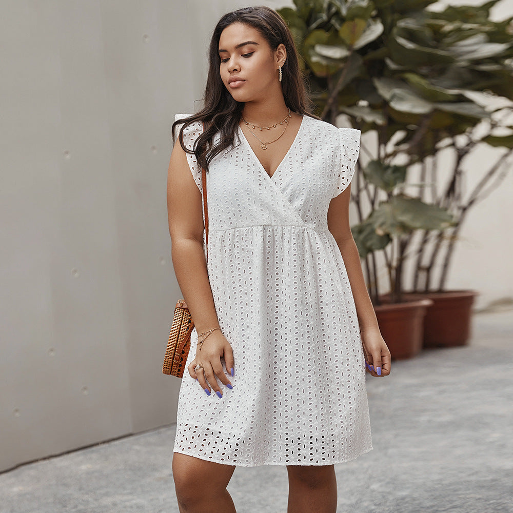 Woman wearing a white dress with black patterns, standing outdoors.