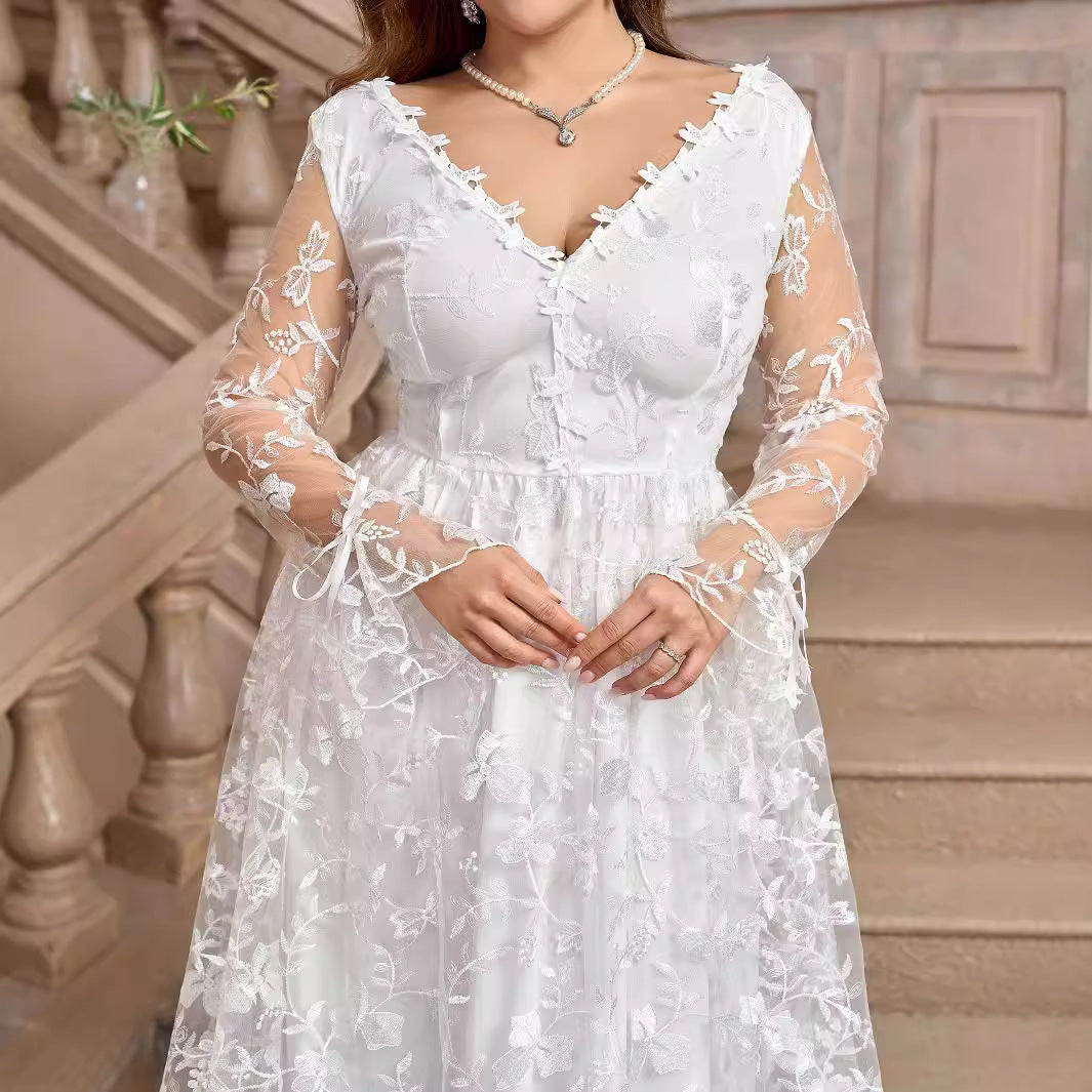 White lace dress with long sleeves worn by a person, set against a neutral indoor background.