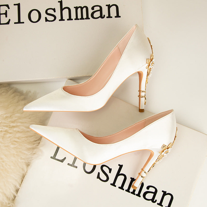 White high-heeled shoes with gold accents on a white surface