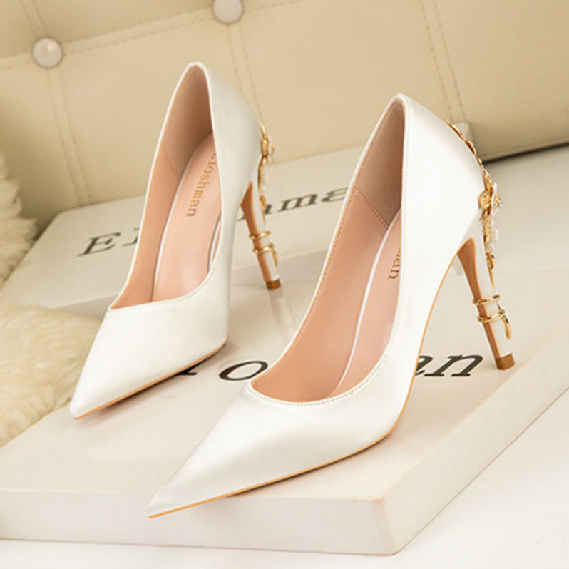 White high-heeled shoes with gold accents on a light background