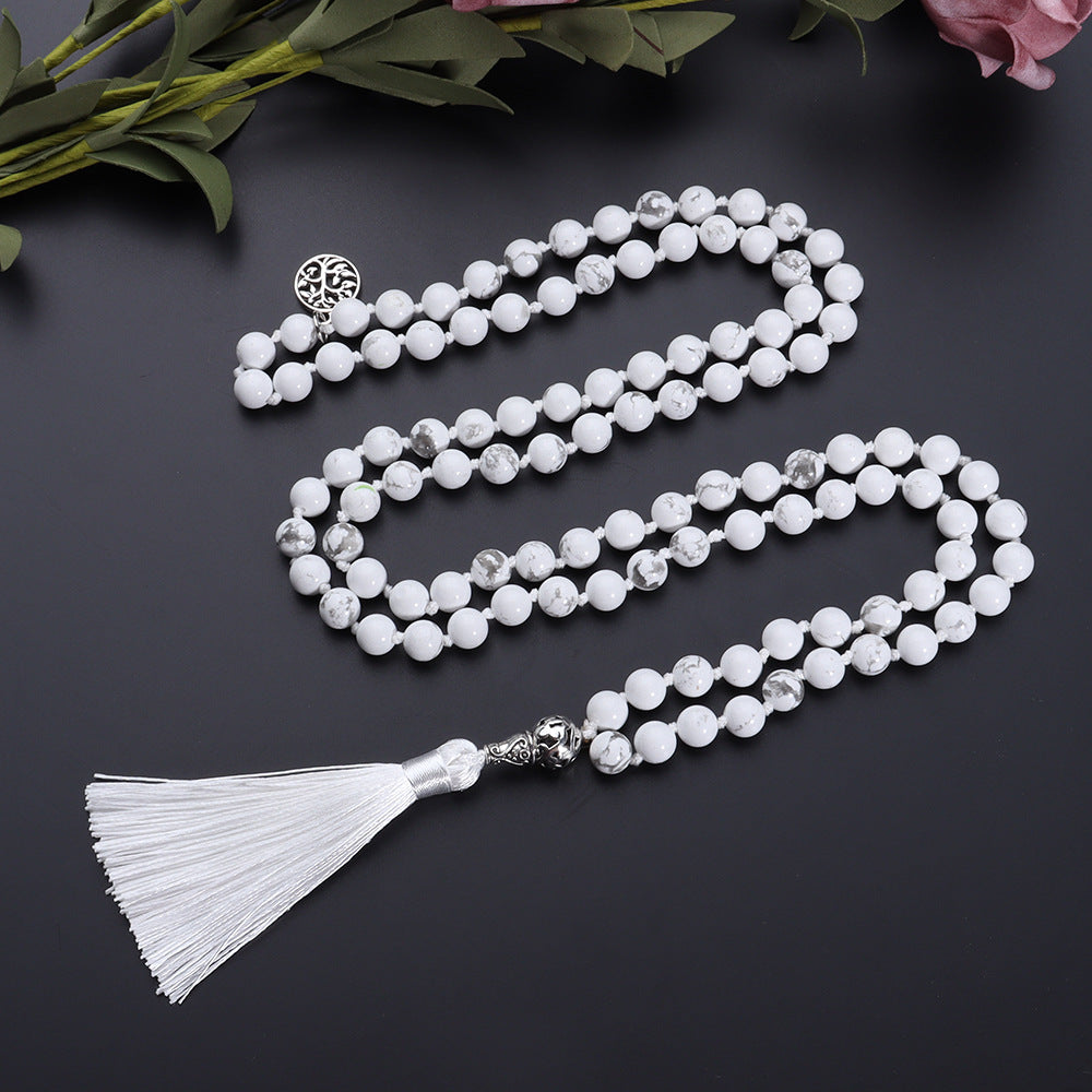 White beaded necklace with tassel on a dark background