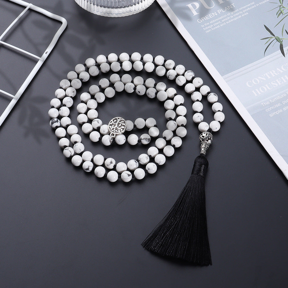 White beaded necklace with tassel on a dark surface