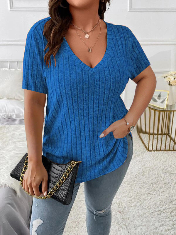 Woman wearing a blue ribbed sweater and holding a black handbag indoors.