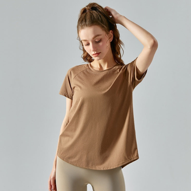 Woman wearing a brown t-shirt and beige leggings against a gray background