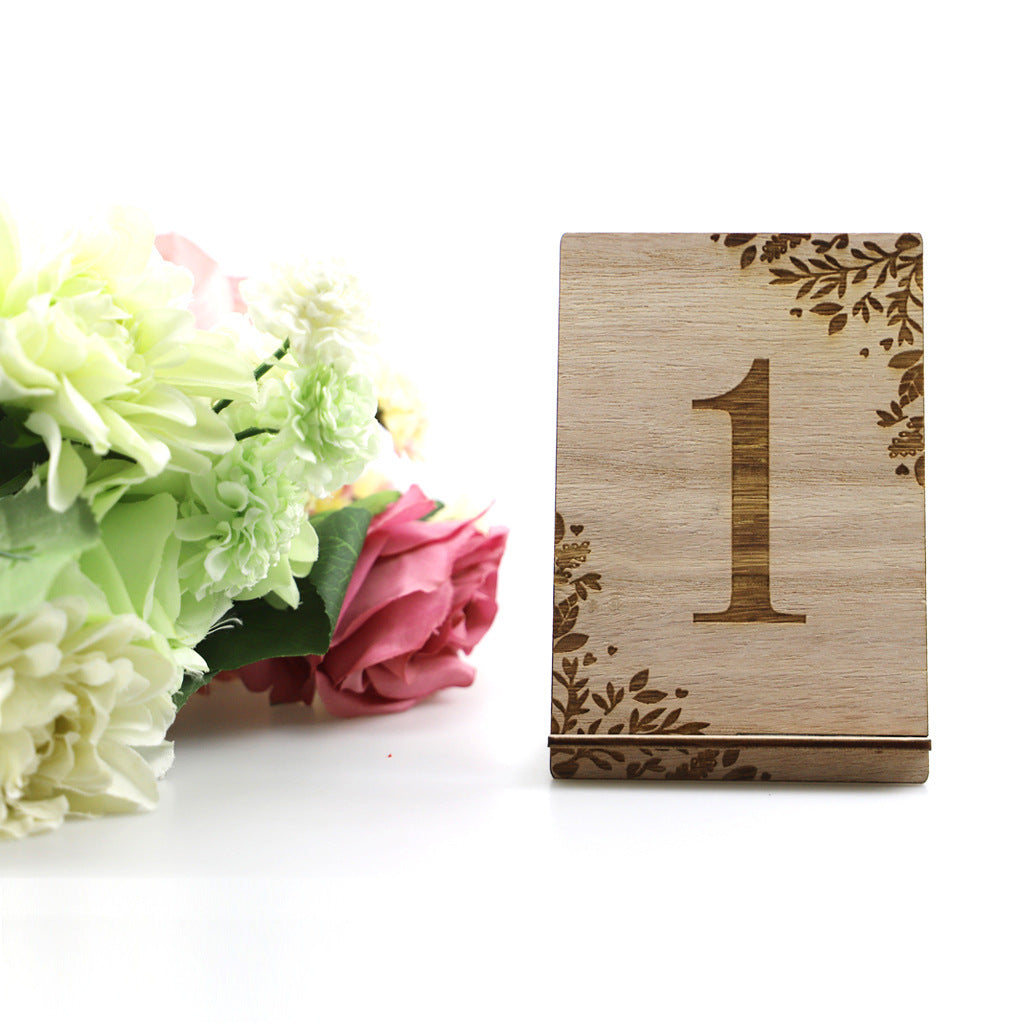 Wooden table number '1' with floral design next to flowers on a white background