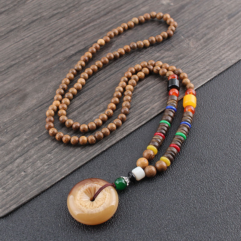 Wooden beaded necklace with a large round pendant on a wooden surface