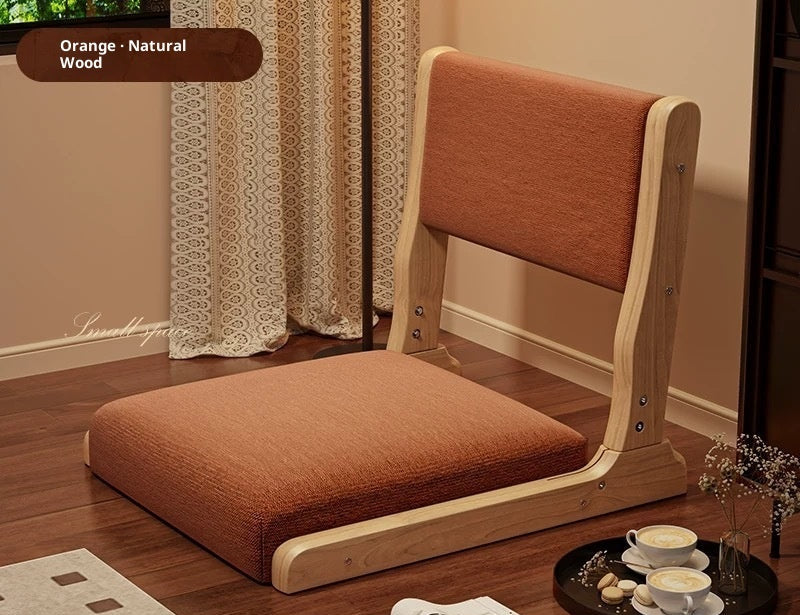 Wooden chair with orange cushion on a wooden floor, surrounded by tea set and decor items.