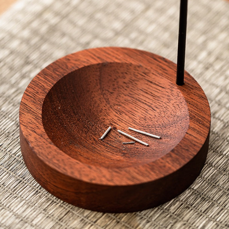 Wooden incense holder with incense sticks on a textured surface