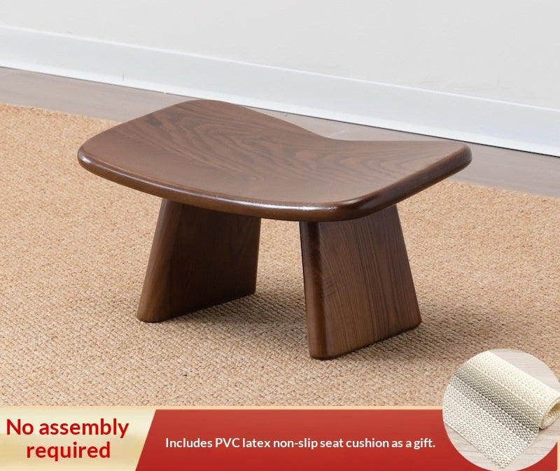 Wooden stool on a carpeted floor with text about height recommendation and assembly requirement.