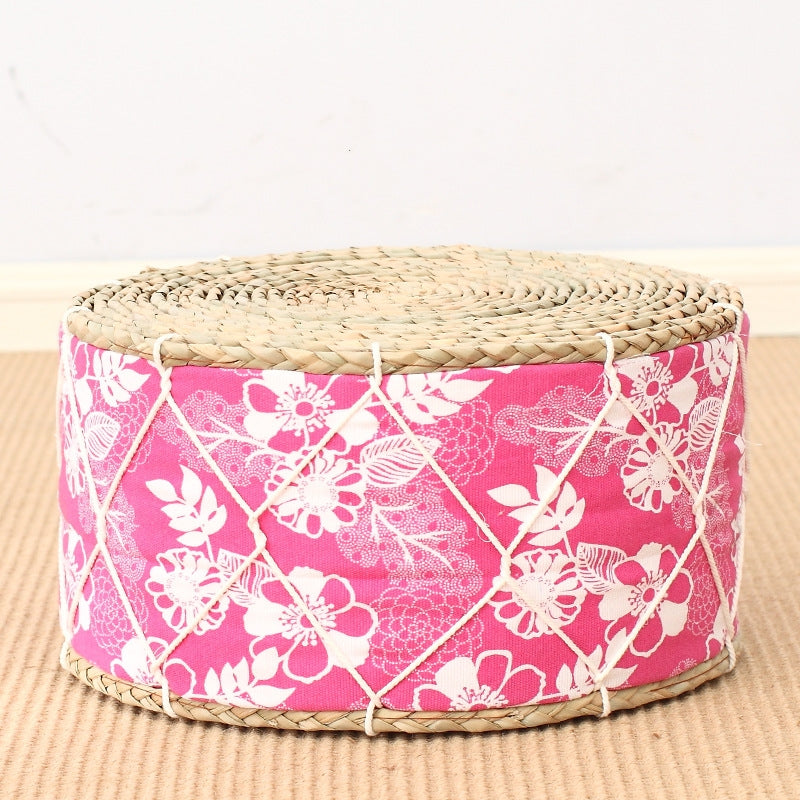 Round woven ottoman with pink floral pattern on a beige background