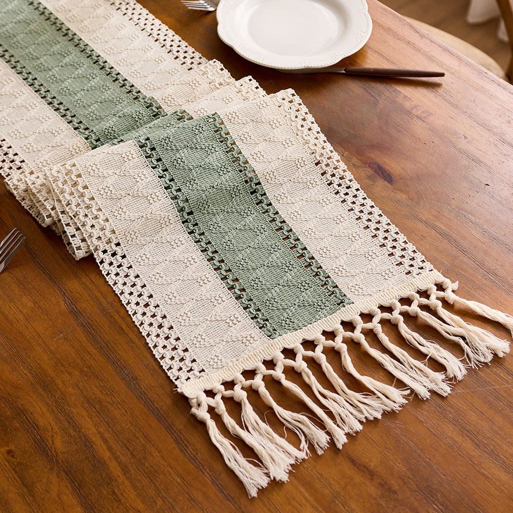 Decorative table runner with green and beige stripes on a wooden table.
