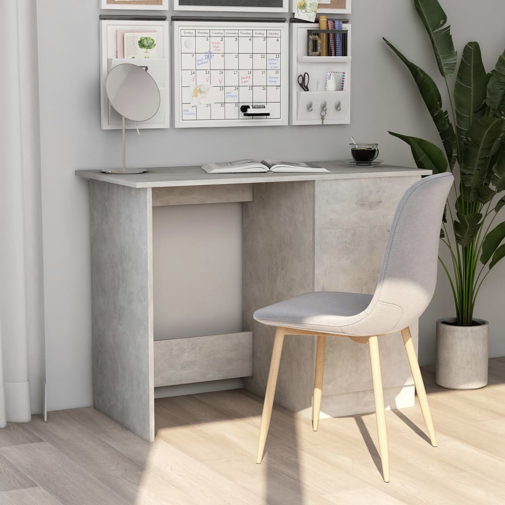 Gray desk with a chair in a room with a plant and wall decorations.