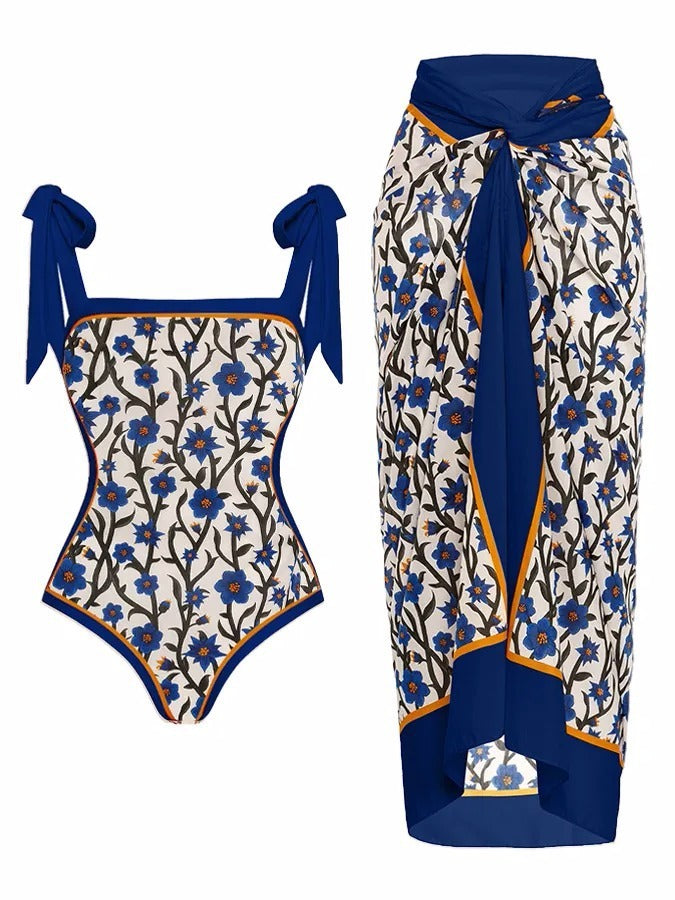 One-piece swimsuit and matching sarong with floral pattern and blue accents on a white background