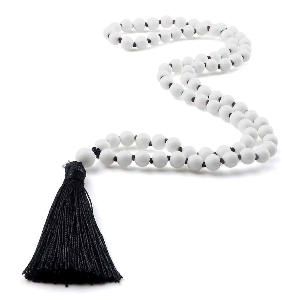White beaded necklace with a black tassel on a white background