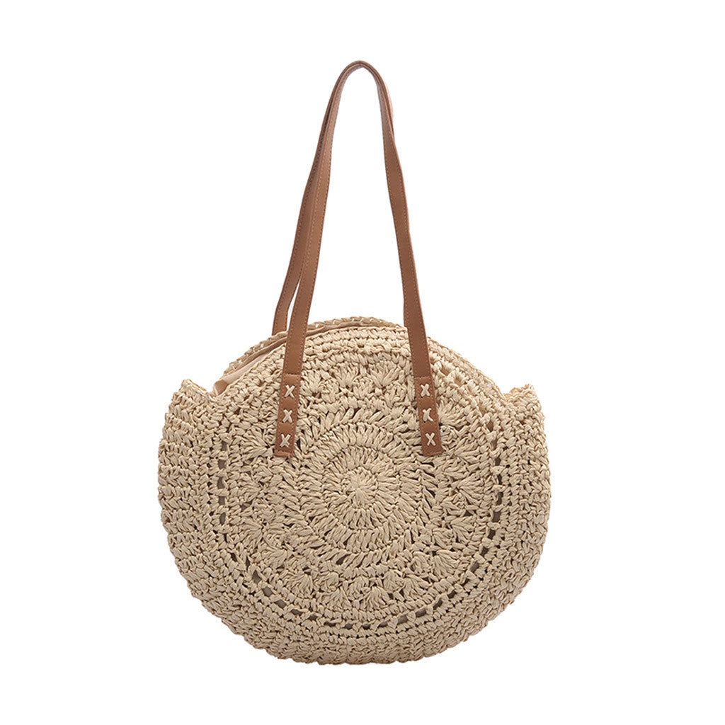 Beige woven handbag with brown leather straps on a white background