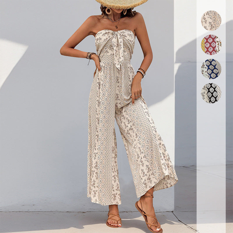 Woman wearing a patterned strapless jumpsuit against a white wall.