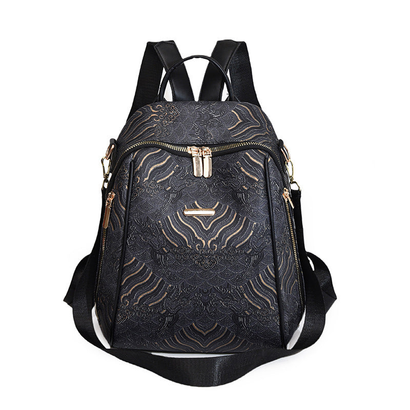 Black backpack with gold patterns and zippers on a white background