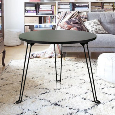 Round black table with metal legs in a living room setting