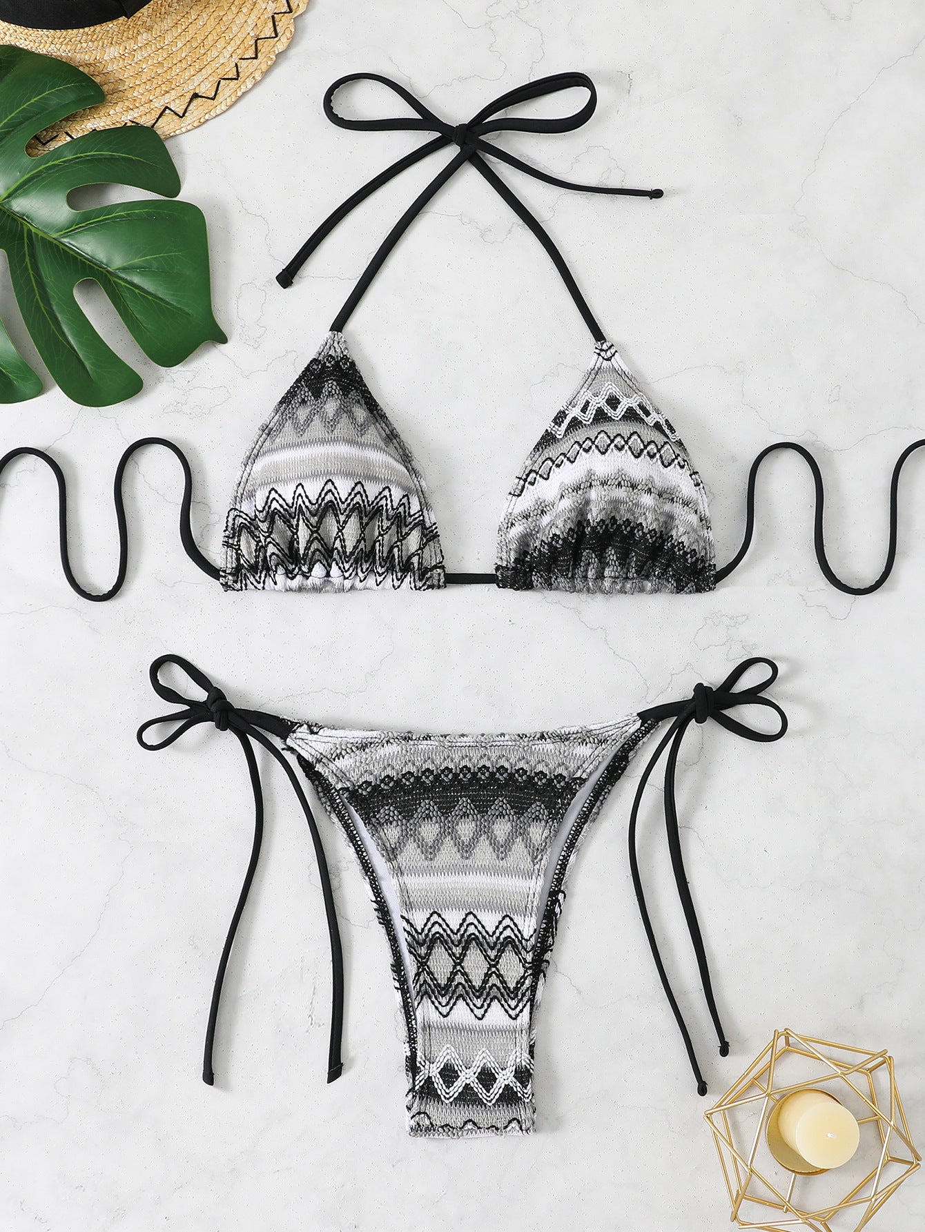 Black and white patterned bikini set on a light background with decorative elements.