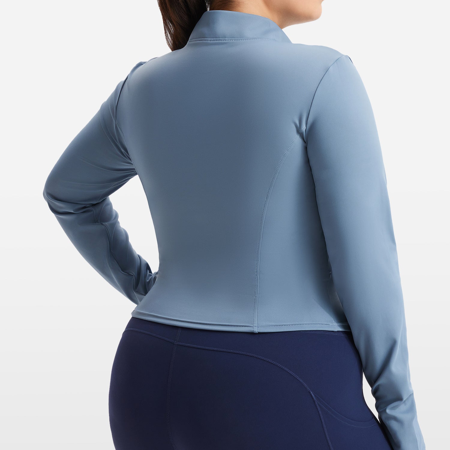 Person wearing a blue athletic top and dark blue leggings on a white background