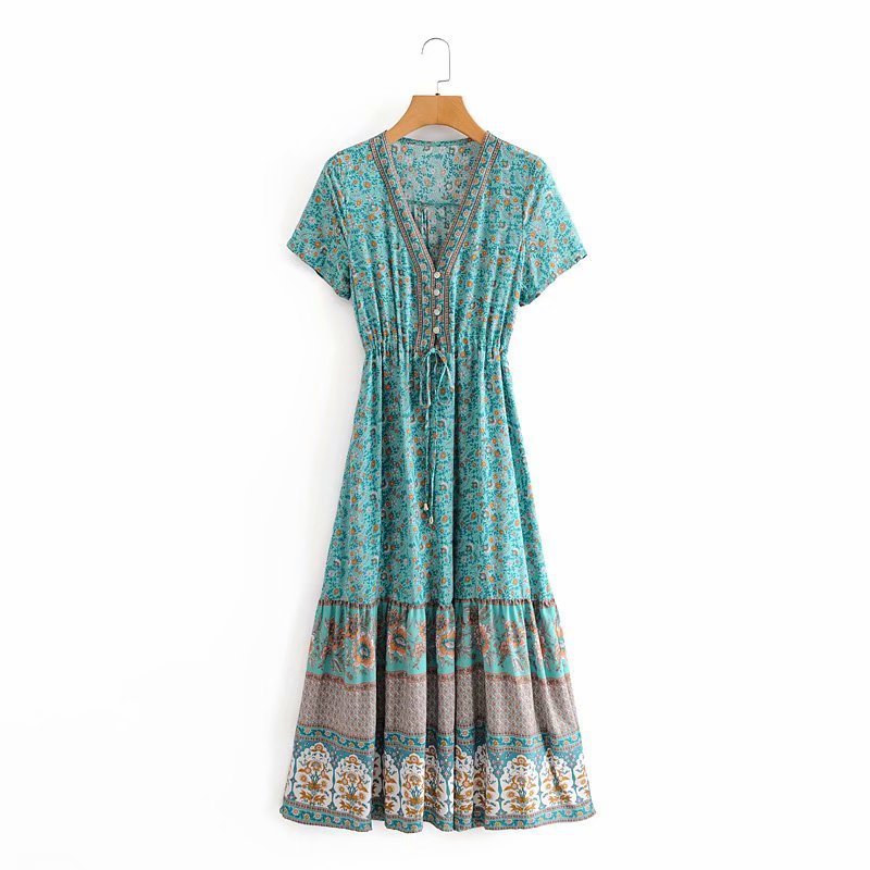 Turquoise patterned dress on a hanger against a white background