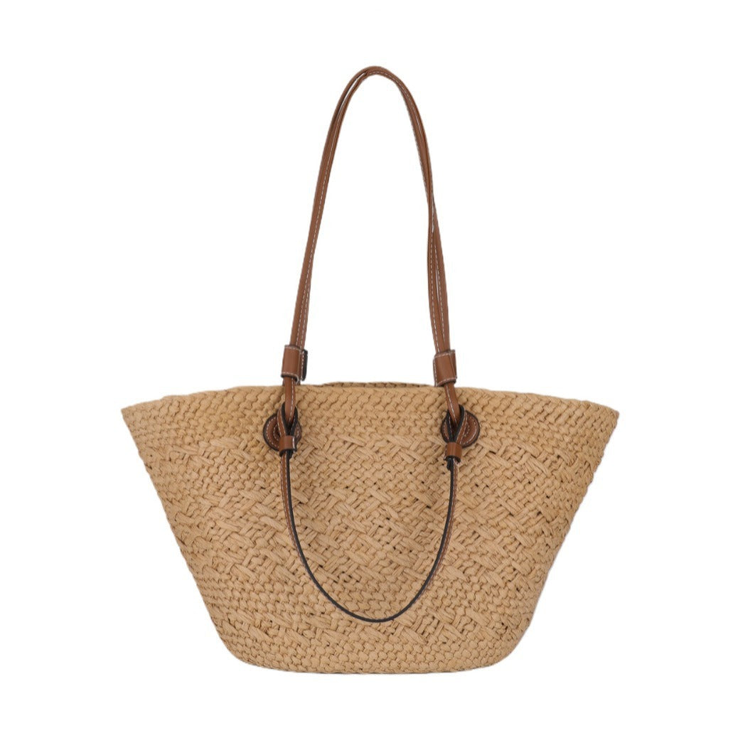 Woven straw handbag with brown leather straps on a white background
