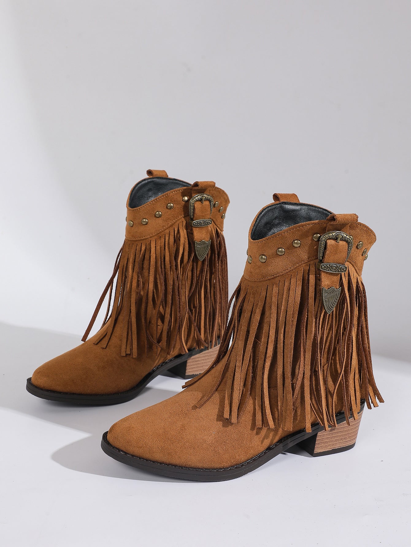 Pair of brown suede fringe boots with buckles on a white background