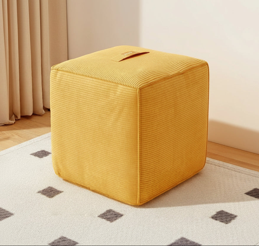 Green cube-shaped ottoman on a patterned rug with a neutral background