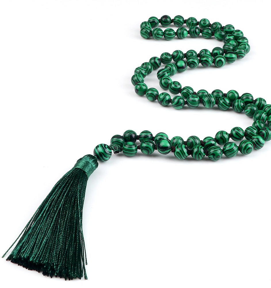 Green beaded necklace with a tassel on a white background