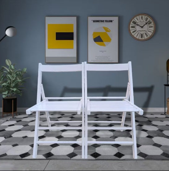 White metal folding chairs on a geometric patterned rug with a gray wall and decorative items.