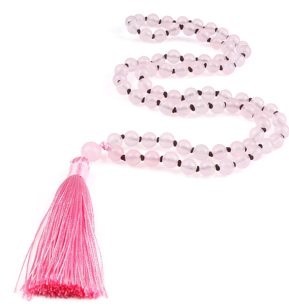 Pink beaded necklace with a tassel on a white background