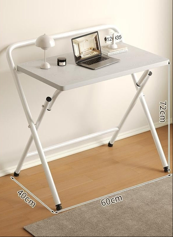 White folding desk with laptop, lamp, and mouse on a wooden floor.