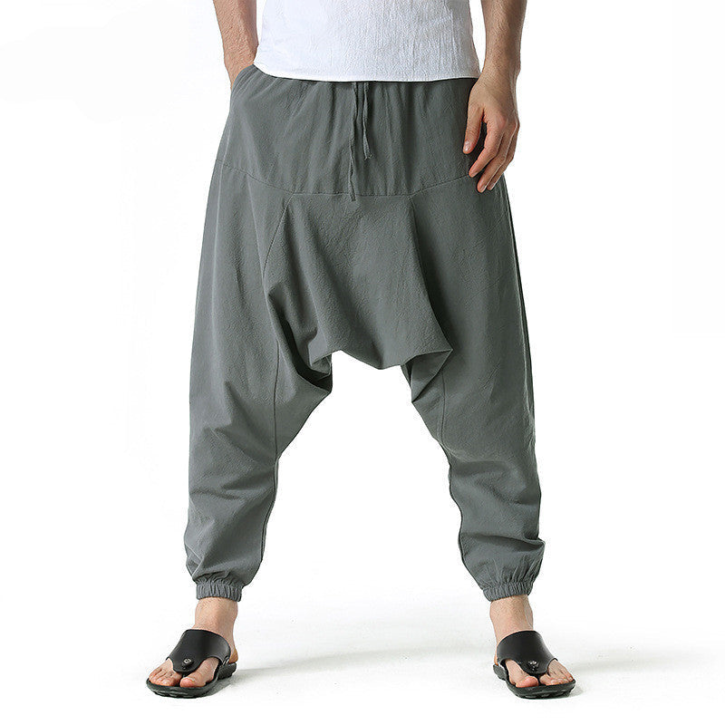 Dark grey harem pants worn by a person on a white background