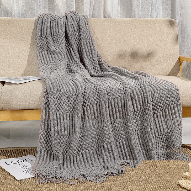 Gray textured blanket draped over a beige sofa in a living room setting.