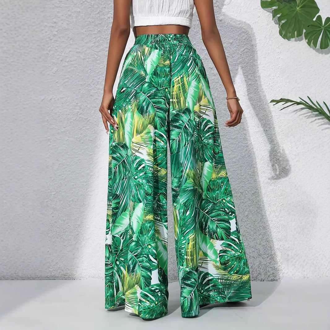 Tropical leaf patterned pants worn by a person on a light gray background