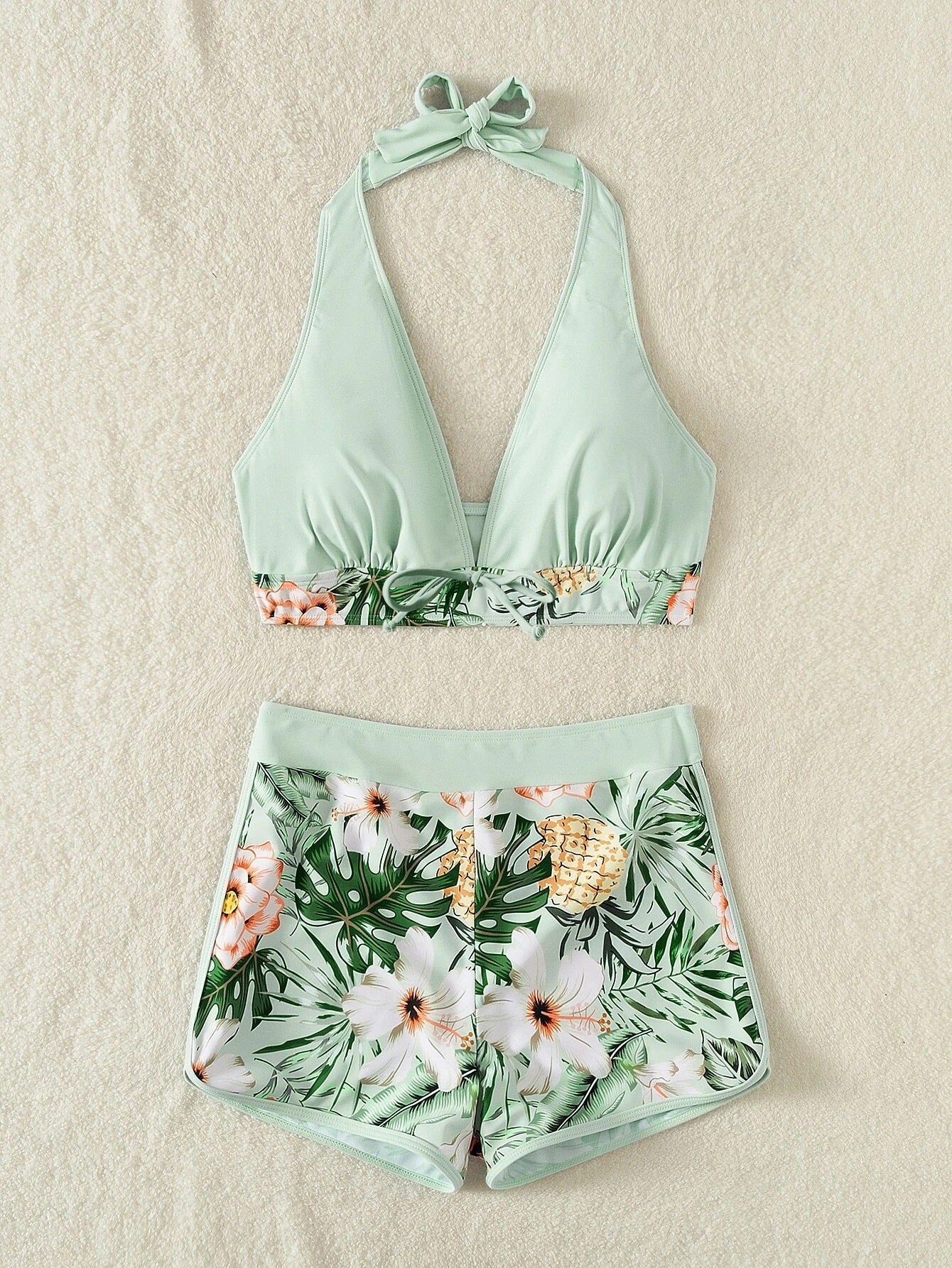 Two-piece swimsuit with floral and pineapple design on a beige background