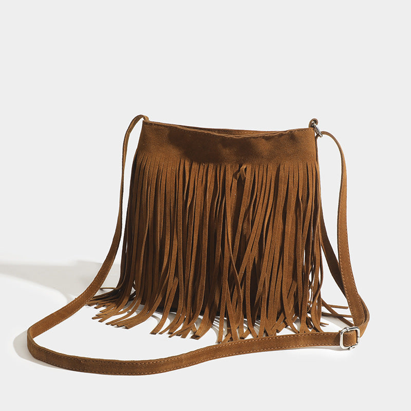 Brown suede handbag with fringe details on a light gray background