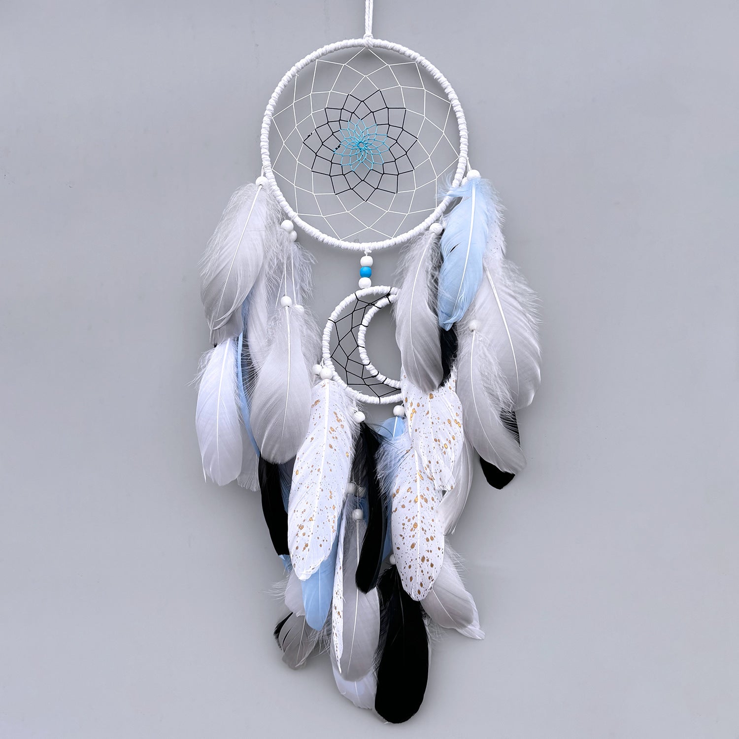 White dreamcatcher with feathers on a gray background