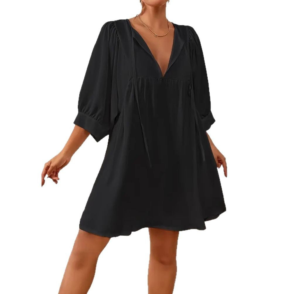 Black dress with a deep neckline and puff sleeves on a white background