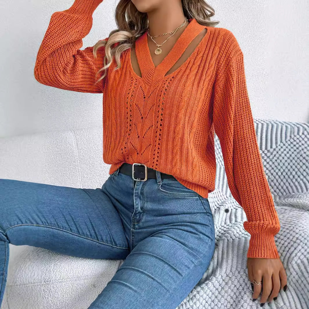 Person wearing an orange knitted sweater and blue jeans sitting on a white couch.