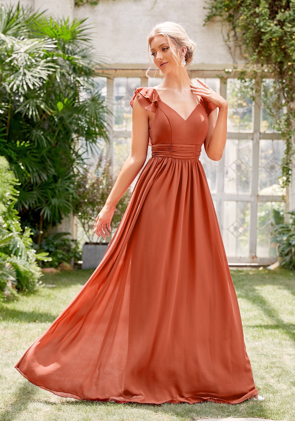 Woman in a rust-colored dress standing in a garden setting