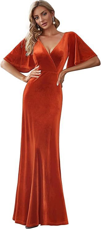 Woman wearing a rust-colored velvet gown with cape sleeves on a white background