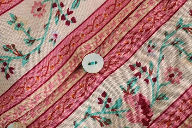 Close-up of a fabric with floral patterns and a button on a pink background