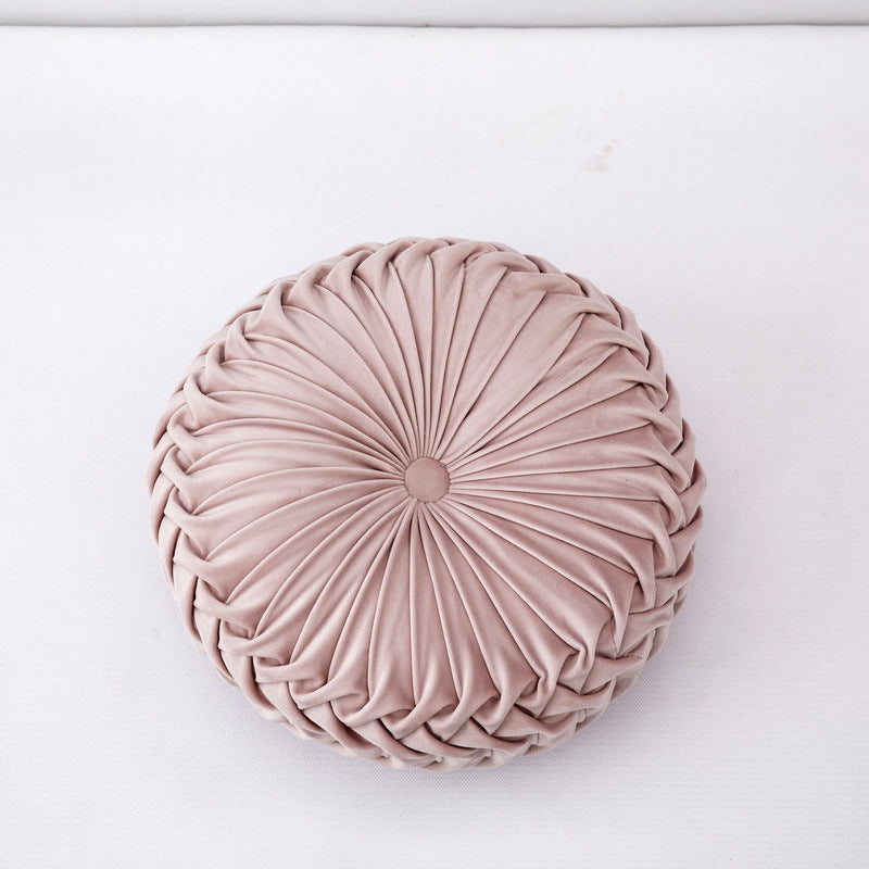 Round, pleated pink cushion on a white background