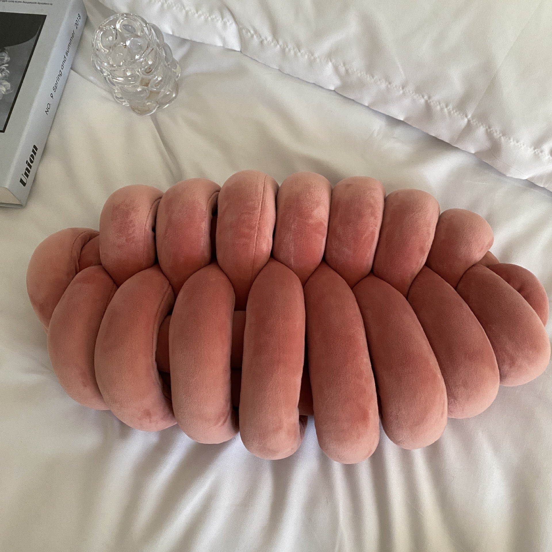 Pink woven cushion on a white surface