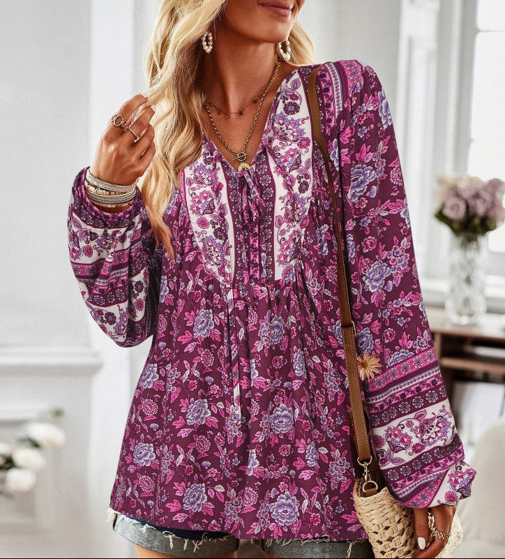 Woman wearing a purple floral blouse in a bright room with flowers in the background