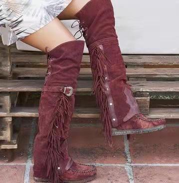 Maroon fringed boots worn by a person sitting on wooden steps.
