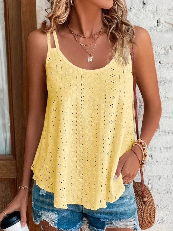 Woman wearing a yellow crochet tank top and denim shorts, holding a coffee cup.